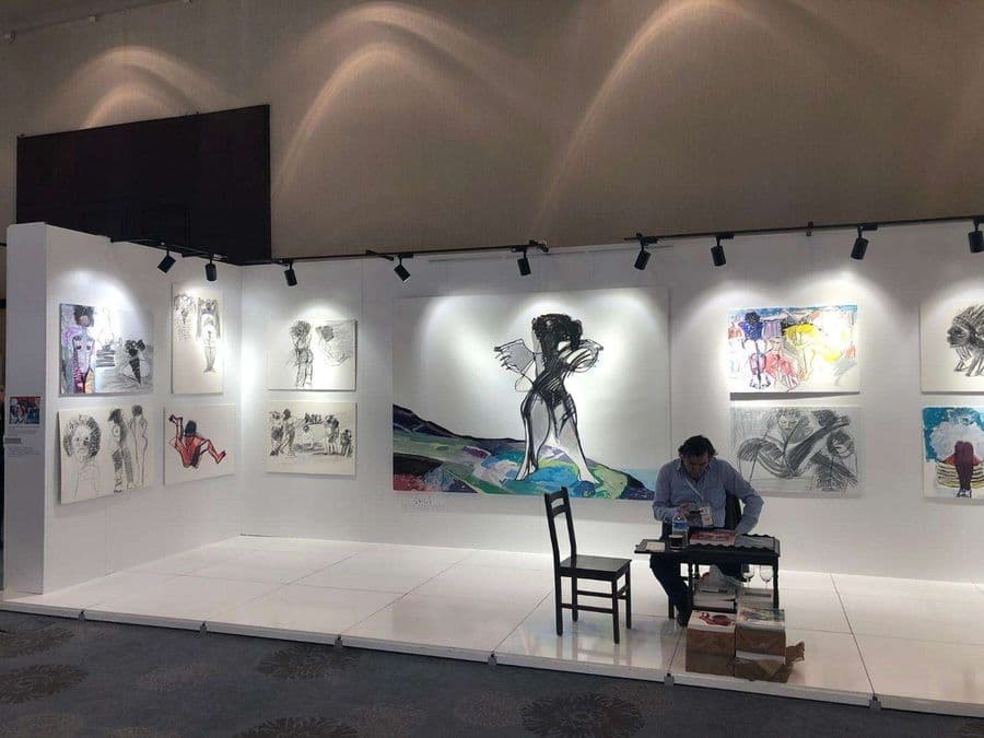 "Asmalı Mescit Sanat Galerisi C-01" isimli standın fuar alanındaki görünümü. Beyaz duvarlarda, figüratif ve dışavurumcu tarzda çizilmiş tablolar sergileniyor.
