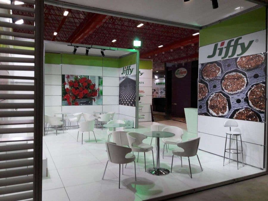 Bahçecilik ürünleri markası "Jiffy"nin bir fuardaki tanıtım standı. Beyaz ve yeşil temalı stantta, bir yanda filizlerin sergilendiği raflar, diğer yanda ise ziyaretçilerin oturduğu masa ve sandalyeler bulunuyor.