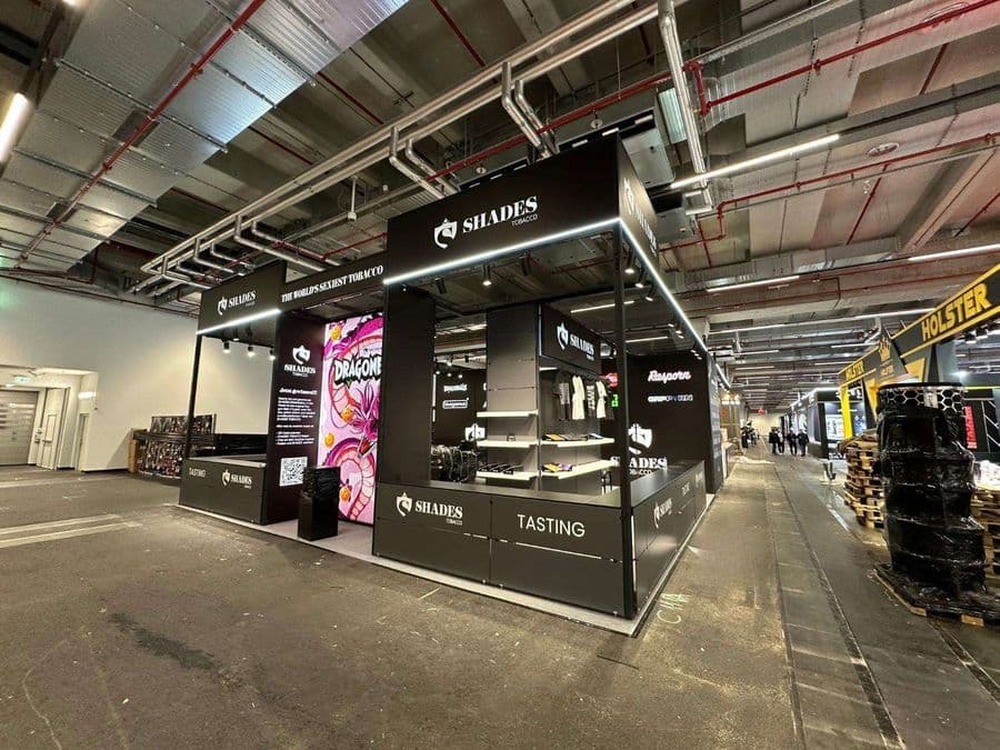 "Chillma Tobacco" markasının şık ve modern fuar standı. Siyah metal iskeletli ve led ışıklandırmalı standın önünde "Tasting" (Tadım) alanı bulunurken, arka duvarda meyvelerle süslenmiş bir kadın portresi yer alıyor.