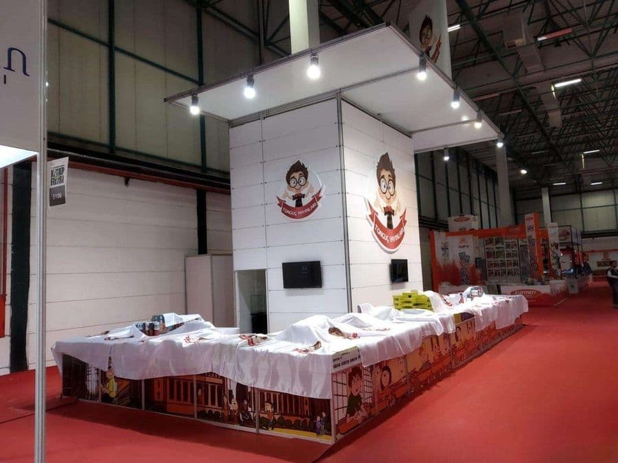 a booth with white table cloths and a red carpet